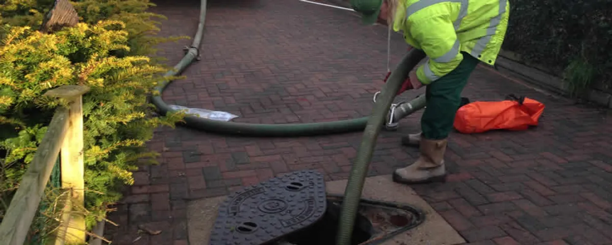 Septic tank cleaning technician servicing a septic tank with a vacuum hose in Tampa, FL