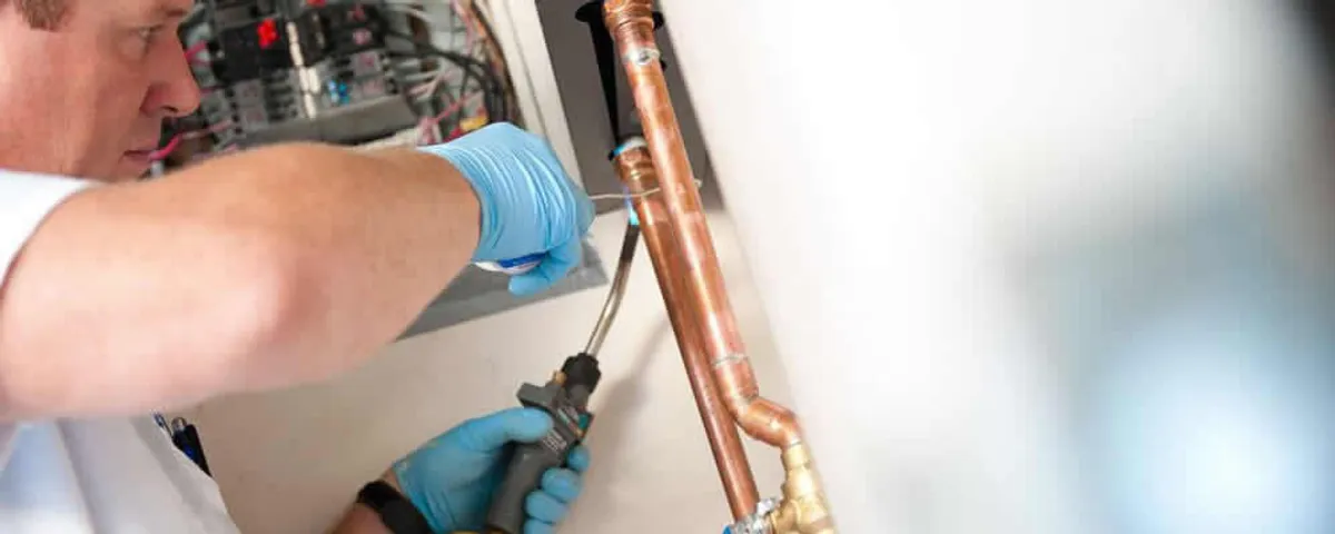 Water heater repair technician testing copper pipe connections and controls in Tampa, FL